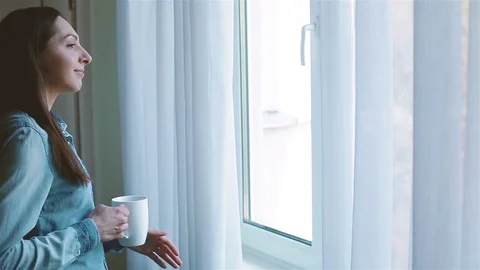 Smiling womn coming to the window with a cup of coffee Stock Footage 129760051