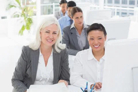 Smiling work team using computer Stock Photos