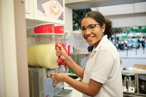 Smiling worker serving a lemon from a drinkk dispenser Stock Photos