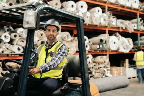 Smiling worker using a forklift to move warehouse stock Stock Photos