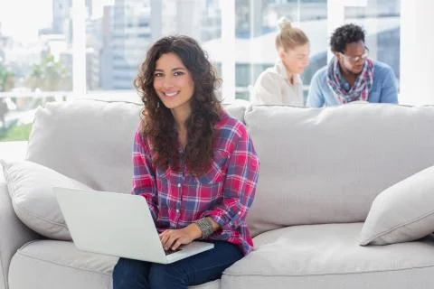Smiling worker using laptop while sitting on a couch 스톡 사진