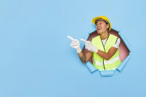 Smiling worker in yellow hard hat, yellow vest and white gloves standing Stock-Fotos
