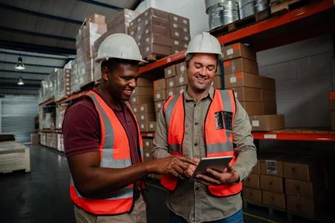 Smiling workers browsing on digital tablet watching funny videos standing in Stock Photos