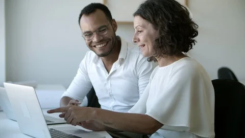 Smiling workers talking and pointing at laptop Stock Footage 117371044