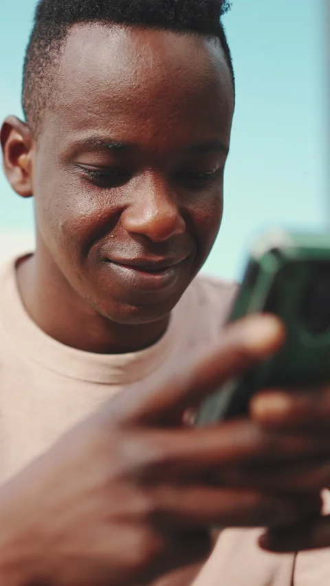 Smiling young african student sits outside of university, uses cellphone, writes Stock Footage 226936027