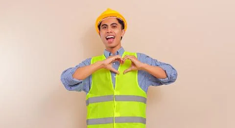 Smiling young Asian construction worker wearing safety vest and hard hat sh.. Stock Photos