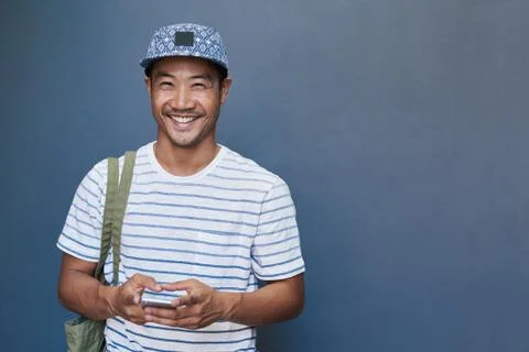 Smiling young Asian man using a cellphone outside Stock Photos