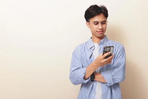 Smiling young Asian man using smartphone with happy expression isolated on .. Stock Photos