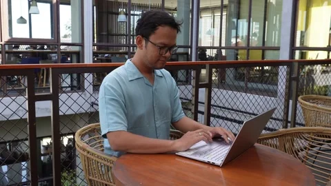 Smiling young Asian man working remotely from cafe using his laptop, employ.. Stock Footage 251622656