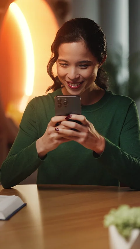 Smiling young Asian woman types on phone, texting through social media app Stock Footage 343665053