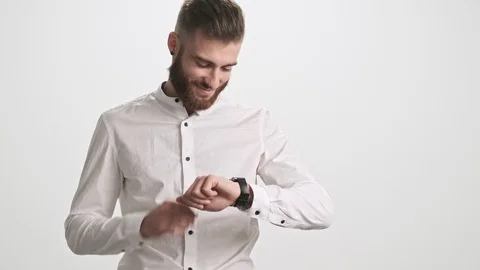 Smiling young bearded man using his smart watch over white background Stock Footage 125320654