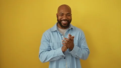 Smiling young black man clapping hands in front of isolated yellow backgrou.. Stock Footage 284261609