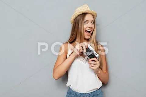 Smiling young blonde girl in hat holding photo camera Stock Photos