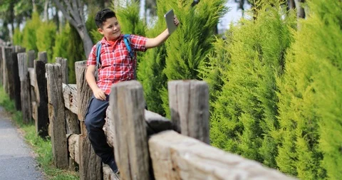 Smiling young boy making selfie photo at the green spring park Stock Footage 105468926