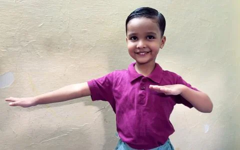 Smiling Young Boy Posing With Outstretched Arms exercise Against a Plain Wall Stock Photos