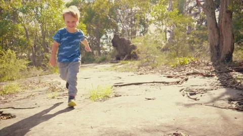 Smiling young boy running toward camera on a bush track slow motion Stock Footage 130225718