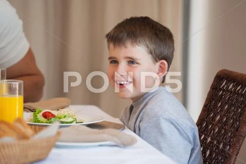 Smiling Young Boy Sitting At Dining Table