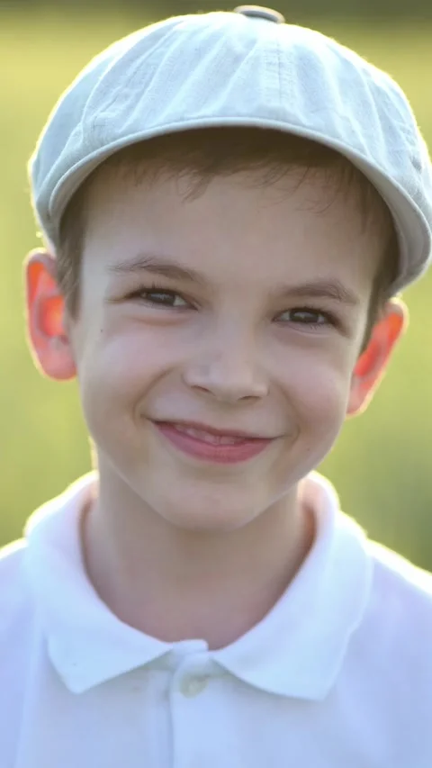 Smiling young boy in white polo and light cap against a wheat field background 스톡 동영상 348790163