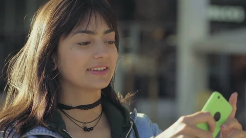 Smiling young brunette with smartphone posing for photo. 動画素材 106274304