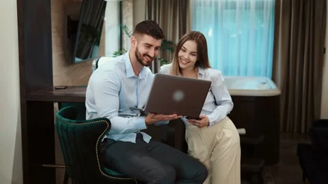 Smiling young business couple using computer at hotel Stock Footage 196541896