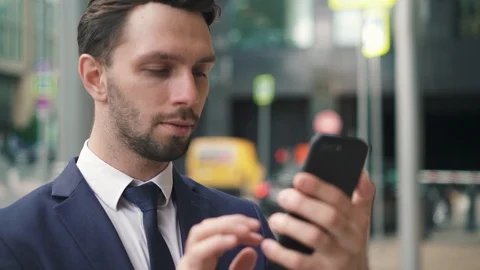 Smiling young businessman using his phone in city street Stock Footage 95591437