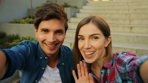 Smiling young caucasian couple having video chat on with the stairs in the Stock Footage 80799025