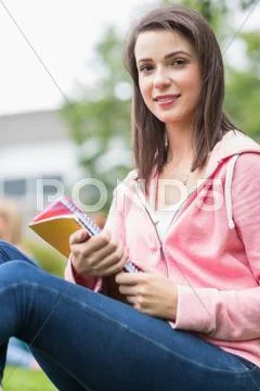 Smiling young college student with books in the park Stock Photos
