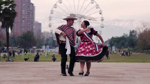 Smiling young couple dressed as Chilean huasos, joyfully dancing cueca outdoors Stock Footage 314416659