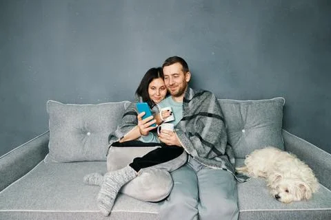 Smiling young couple embracing while looking at smartphone Stock Photos