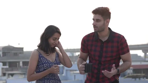 Smiling young couple having coffee while talking outdoors and laughing together. Video stock 148978351