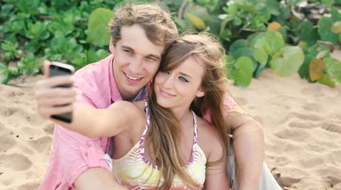 Smiling young couple in love taking self portrait with camera phone on beach Stock Footage 58162197