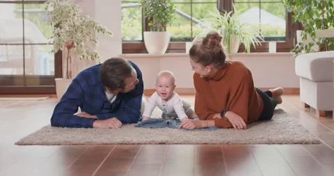 Smiling young couple lying together on rug on their living room floor at home 库存影片 140189121