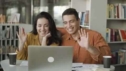 Smiling young couple making video call on laptop waving hand Stock Footage 143218531