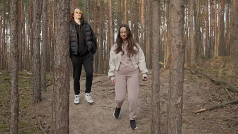 A smiling young couple talking while walking downhill in a scenic pine forest Stock Footage 315072510