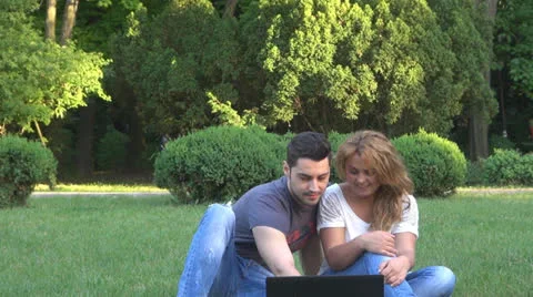 Smiling young couple using computer in park Stock-Footage 23907660