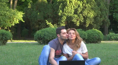Smiling young couple using computer in park 스톡 동영상 23907825