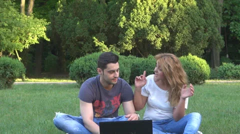 Smiling young couple using computer in park 스톡 동영상 23907980