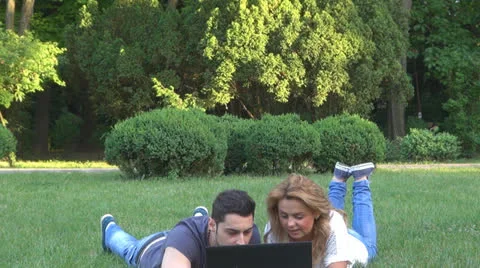 Smiling young couple using computer in park 스톡 동영상 23908269