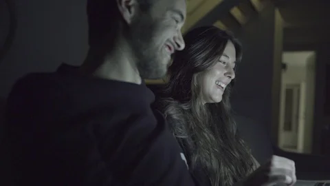 Smiling young couple using laptop together at night Stock Footage 100548033