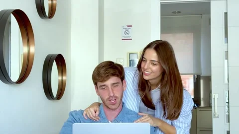 Smiling young couple using a laptop together for online shopping and planning Stock Footage 347197282