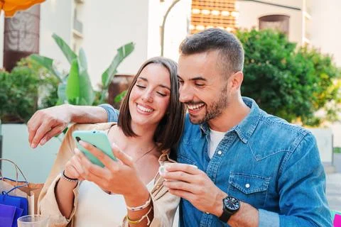 Smiling young couple using a smartphone chatting online on social media and Stock-Fotos