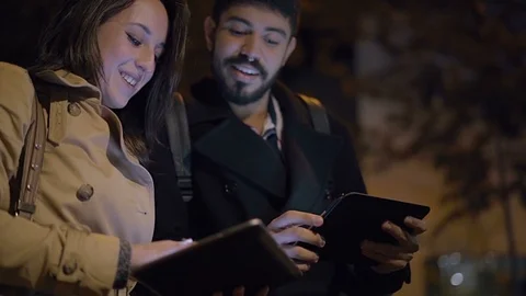 Smiling young couple using tablet computers on street Stock Footage 100893540