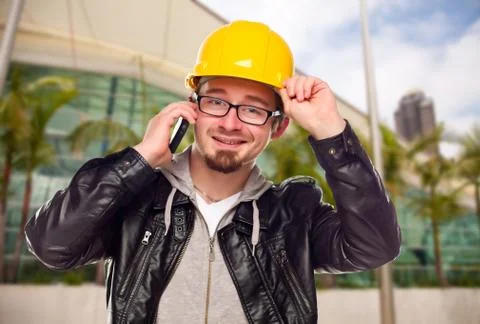 Smiling Young Cunstruction Worker Talking on Cell Phone In Front of Building. Stock Photos