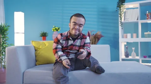 Smiling young disabled man using smartphone at home. Video stock 230974469