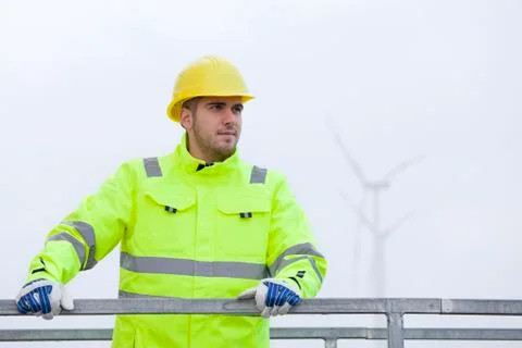 Smiling young engineer with hard hat and protective clothing in front of blur Stock Photos
