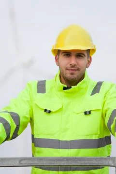Smiling young engineer with hard hat and protective clothing in front of blur Stock Photos