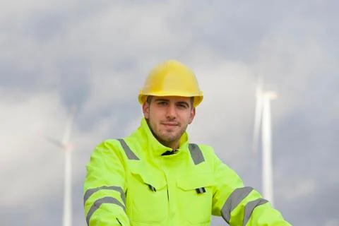 Smiling young engineer with hard hat and protective clothing in front of blur Stock Photos
