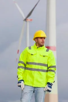 Smiling young engineer with hard hat and protective clothing in front of blur 写真素材