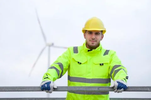 Smiling young engineer with hard hat and protective clothing in front of blur Stock Photos