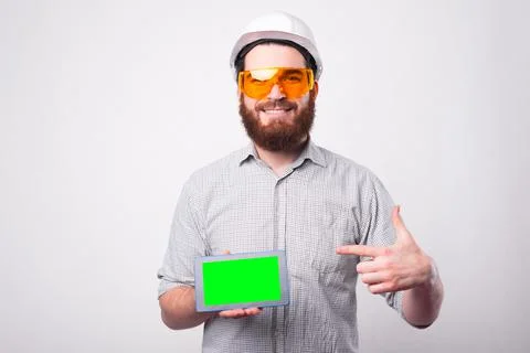 Smiling young engineer pointing at green screen on tablet and wearing white Stock Photos